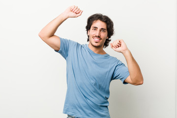 Fototapeta premium Young handsome man against a white background celebrating a special day, jumps and raise arms with energy.