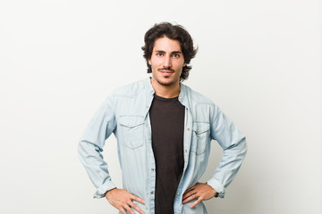 Young handsome man against a white background confident keeping hands on hips.