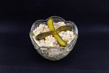 Olivier salad with pickles and baked meat on a black background.