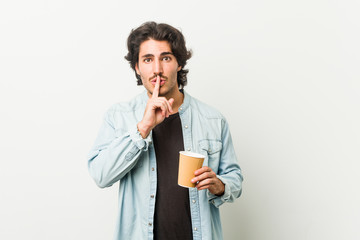 Young cool man drinking a coffee keeping a secret or asking for silence.