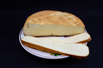 Caucasian smoked Suluguni cheese close-up on a black background.
