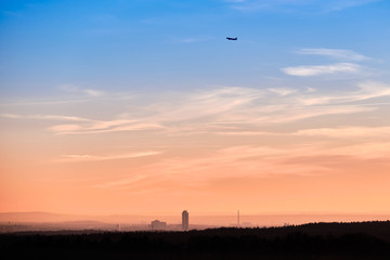 Beautiful sunset landscape with the skyline of Nuremberg and an aeroplane starting into the sky. Seen in Bavaria, Germany in January from Tauchersreuth.