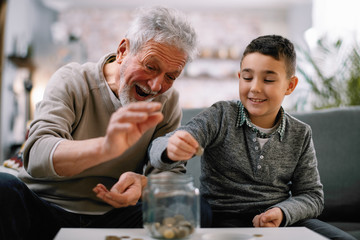 Grandpa and grandson saving money. Grandfather teaching grandchild how to save money.  
