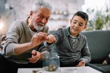 Grandpa and grandson saving money. Grandfather teaching grandchild how to save money.  