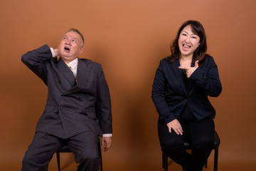 Mature Asian businessman and mature Asian businesswoman having different opinions together