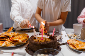 children light candles on a birthday cake on a white table