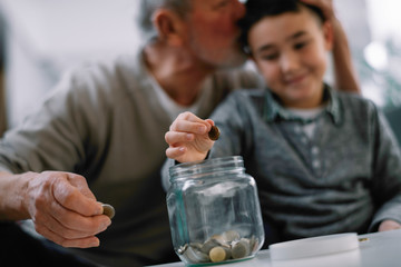 Grandpa and grandson saving money. Grandfather teaching grandchild how to save money.  