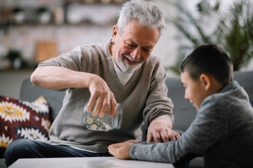 Obraz premium Grandpa and grandson saving money. Grandfather teaching grandchild how to save money. 