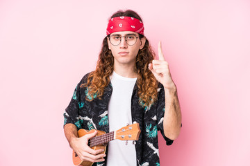 Long hair hippie man holding a ukelele isolated showing number one with finger.