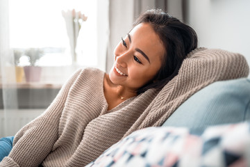 Relaxed smiling asian woman sitting on sofa at home