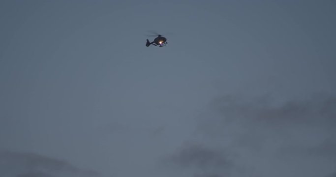 Police Helicopter Flying In Front Of Dark Sky, Light Attached To Search For A Person.