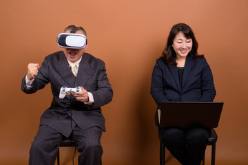 Mature Asian businesswoman with mature Asian businessman playing games