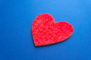 Fototapeta premium Blurred red colored wooden heart at classic blue background. Love concept.