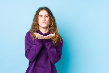 Long hair man posing isolated folding lips and holding palms to send air kiss.