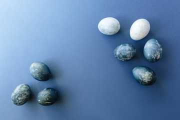 Beautiful group ombre blue Easter eggs with quail eggs and feathers on a blue background. Easter concept. Border eggs. Copy space for text.