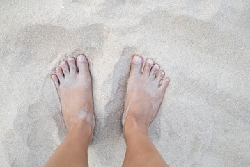 Closeup of woman tanned barefoot standing on white sand beach. Travel concept. Happy feet in tropical paradise.