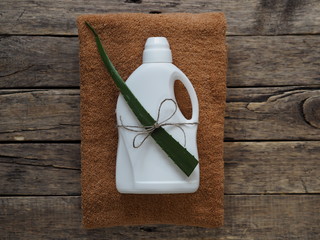 The concept of organic detergent in the form of a green leaf and a white plastic bottle of detergent on a wooden natural background. In conjunction with the green leaf of the medicinal plant aloe vera