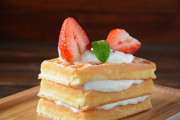 Belgian waffles with strawberries, whipped cream and mint leaves. Tasty dessert concept