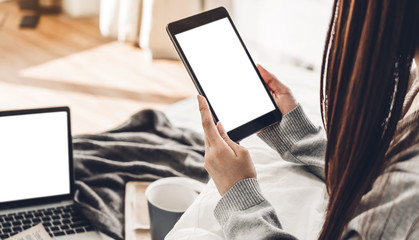 Woman relaxing and using digital tablet computer with white mockup blank screens on the bed at home.woman checking social apps and working.Communication and technology concept