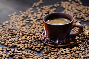 Cup of hot coffee and coffee beans on the table close-up.