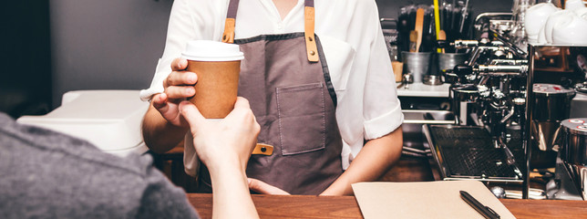 Woman barista giving coffee cup to customer at cafe