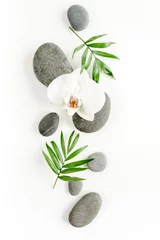 Foto op Plexiglas Spa stenen, palmbladeren, bloem witte orchidee en zen zoals grijze stenen op een witte achtergrond. Platliggend, bovenaanzicht © K.Decor