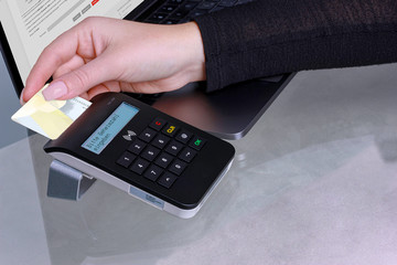 Cropped view of womens hand using a smartcard reader for online-banking.
