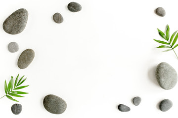 Spa stones, palm leaves, candle and zen like grey stones on white background. Flat lay, top view - Powered by Adobe