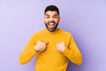 Young mixed race arabic man isolated surprised pointing with finger, smiling broadly.