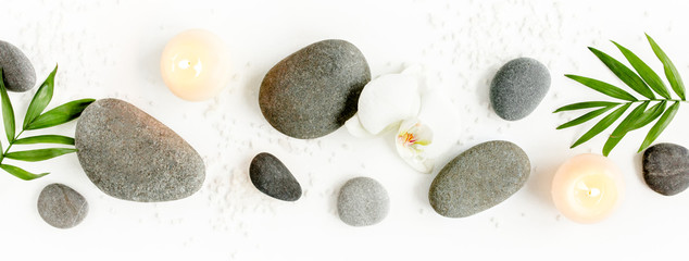 Spa stones, palm leaves, flower white orchid, candle and zen like grey stones on white background....