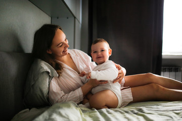 Tender mom and chubby toddler baby on bed together