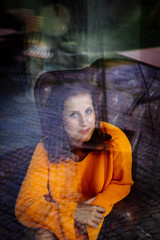 Obraz premium Young woman sitting thoughtfully in a leather armchair behind a window