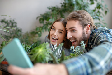 Smiling man and woman making selfie with suculent plants