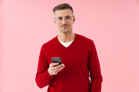 Portrait of handsome caucasian man smiling and holding smartphone