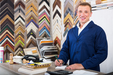 concentrated man seller in picture framing studio with wooden details