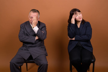 Obraz premium Mature Asian businessman and mature Asian businesswoman thinking together