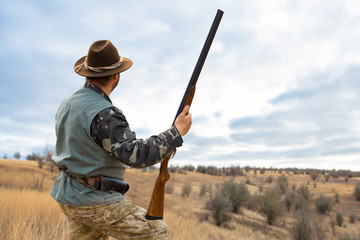 Hunter man in camouflage with a gun during the hunt in search of wild birds or game. Autumn hunting...