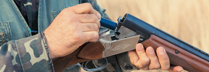 Close up of hunter loading shotgun. Holds a gun and ammunition in his hand.