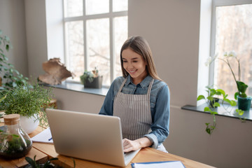 Young woman wearing an apron working with a computer