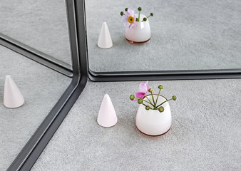 Pink cone and vase with Japanese anemone and its reflection in mirror.