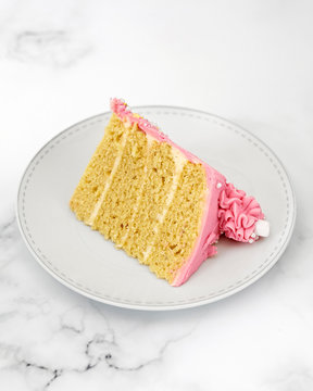 Vanilla cake slice with pink frosting on plate