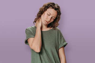 Tired upset young caucasion woman suffering from fatigued massaging hurt stiff neck