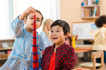 Selective focus of kids playing educational game with teacher and child at background in montessori...