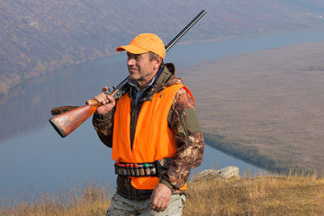 Hunter man in camouflage with a gun during the hunt in search of wild birds or game. Autumn hunting season.