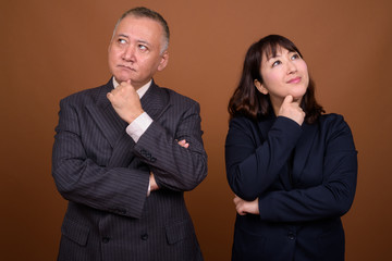 Mature Asian businessman and mature Asian businesswoman thinking together