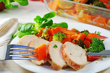 Oven-fried chicken breast slices served with sweet potato salad and vegetable salad on white plate