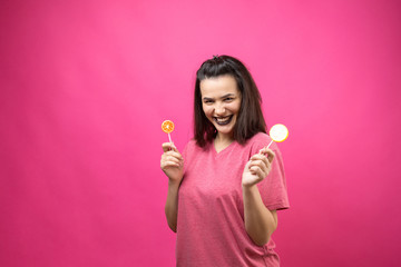 Portrait of lovely sweet beautiful cheerful woman with straight brown hair holding a lollipop near the eyes.