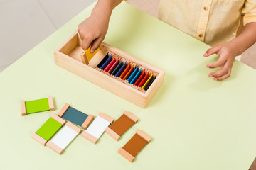 Cropped view of kid playing educational game with colorful boards at table in montessori school