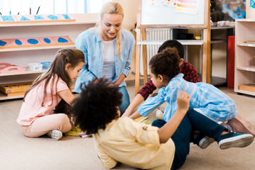 Obraz premium Selective focus of teacher and kids playing game on floor in montessori school