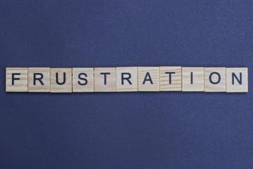 gray word frustration from small wooden letters on a black table
